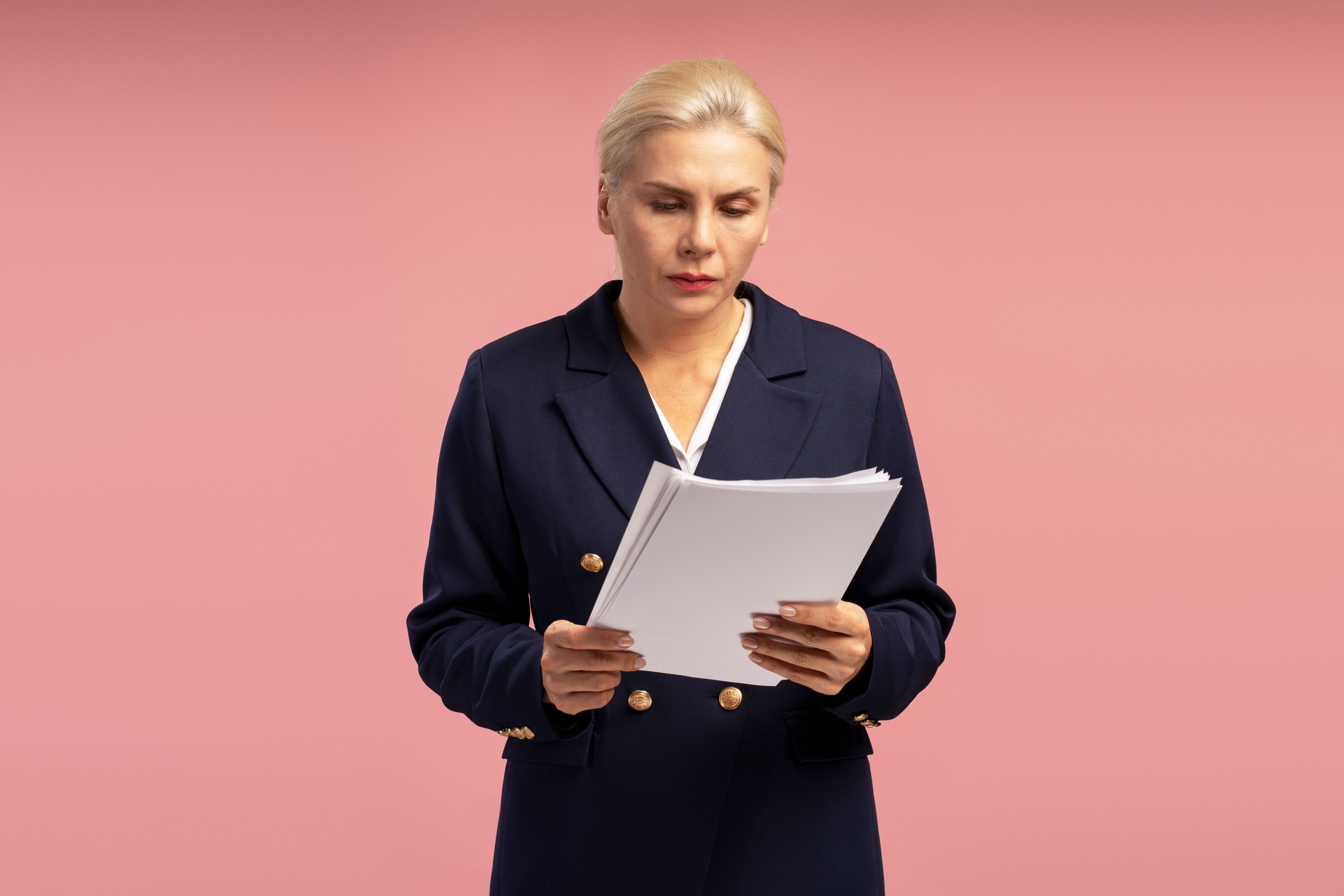Businesswoman reading documents on pink background